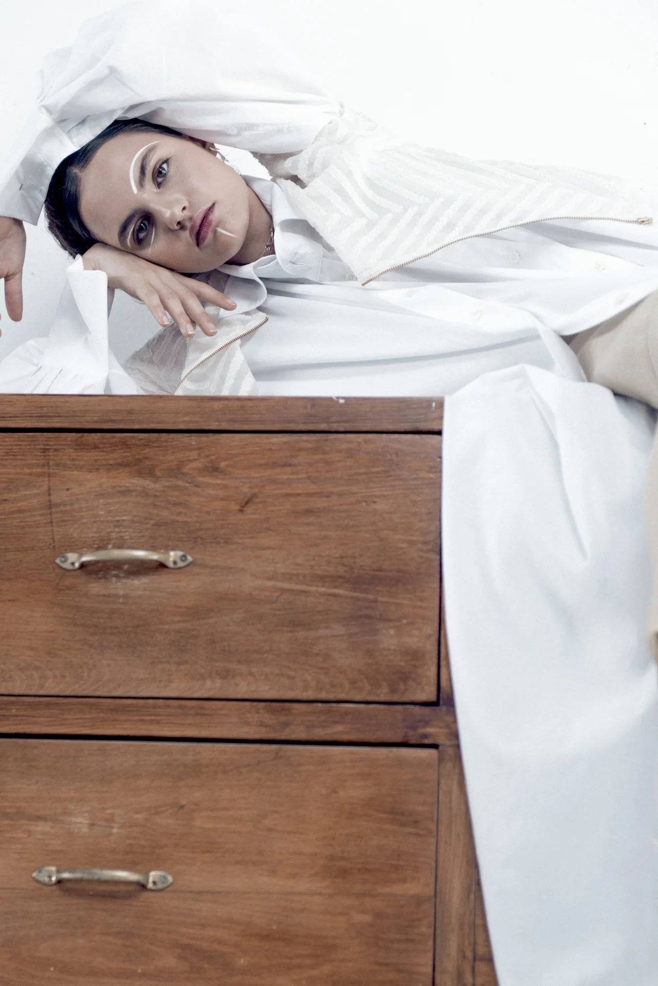 Maquillaje artístico de líneas blancas, recostada sobre una cómoda de madera